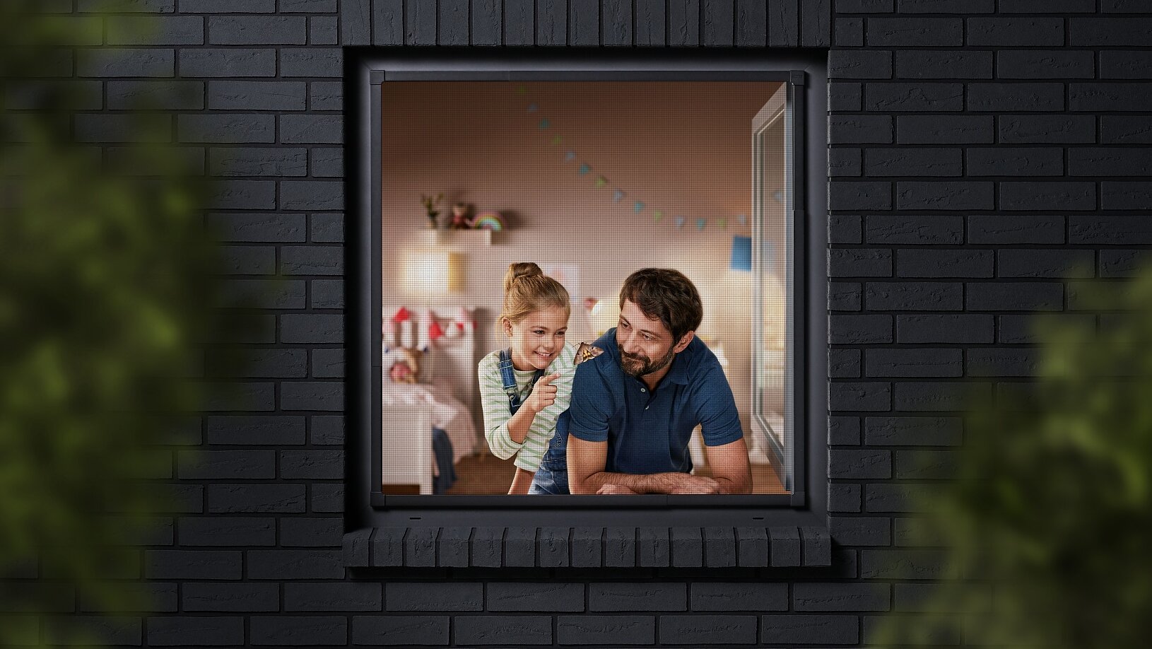 A man and a child are seen through a window, looking into a room decorated with colorful bunting. The building has dark brick walls, and the view is partially framed by blurred greenery. The man is wearing a blue shirt, and the child is sitting beside him. (This text has been generated by AI)