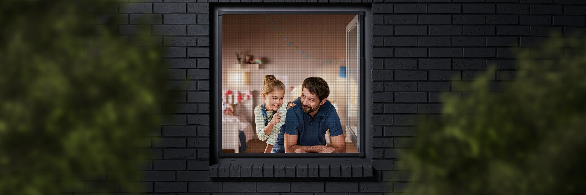 A man and a child are seen through a window, looking into a room decorated with colorful bunting. The building has dark brick walls, and the view is partially framed by blurred greenery. The man is wearing a blue shirt, and the child is sitting beside him. (This text has been generated by AI)