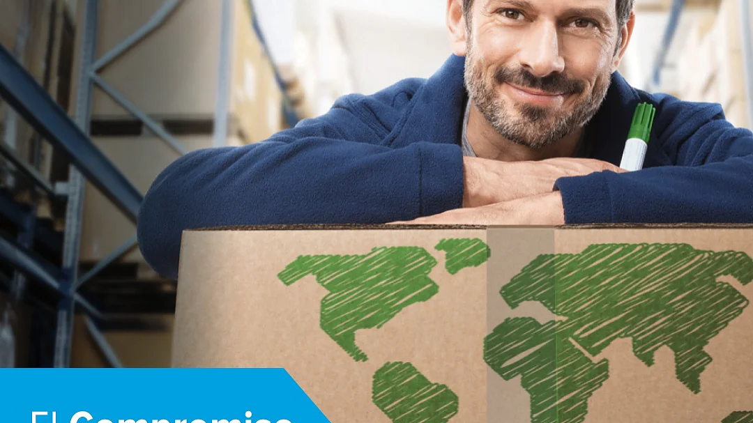 Un hombre con barba se apoya sobre una caja de cartón con un diseño de mapamundi. Sostiene un rotulador. El texto en español dice El compromiso con un ambiente más sostenible, junto al logotipo de tesa. El entorno parece ser un almacén. (This text has been generated by AI)
