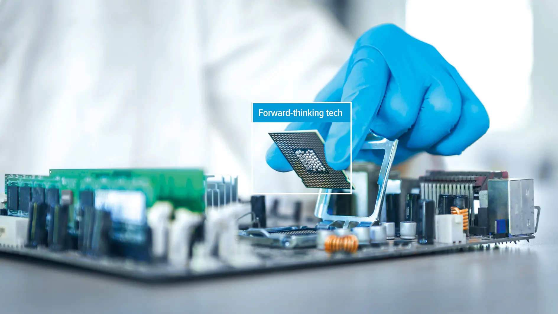 A person wearing a blue glove installs a computer processor onto a motherboard using tesa tape. The phrase Forward-thinking tech appears over the processor. (This text has been generated by AI)