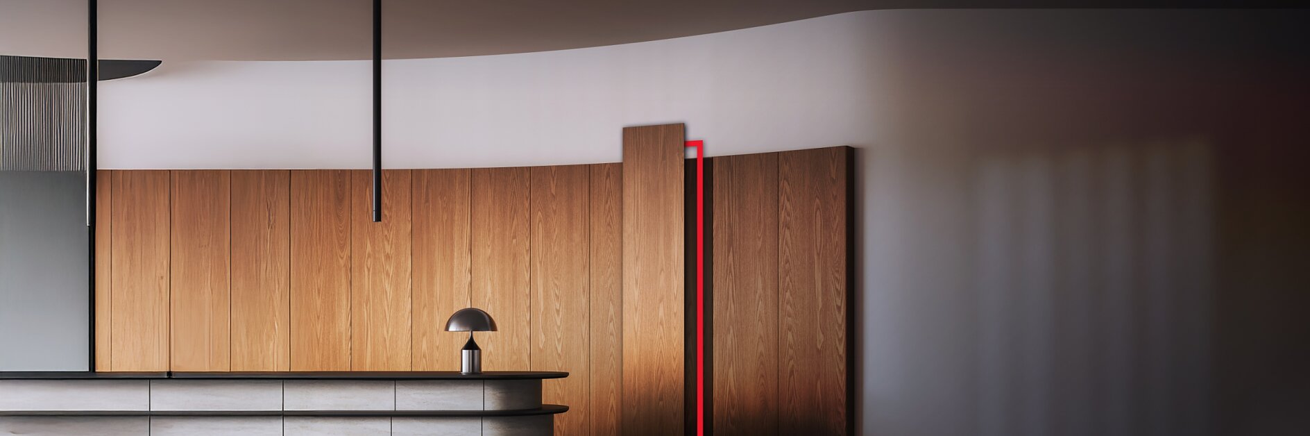 Interior moderno con una pared curva de madera clara, una puerta oculta parcialmente abierta resaltada por un contorno rojo fijado con cinta adhesiva Tesa, una encimera curva de color gris claro, una pequeña lámpara gris y unos discretos apliques negros en el techo. La escena está iluminada por una luz suave e indirecta.