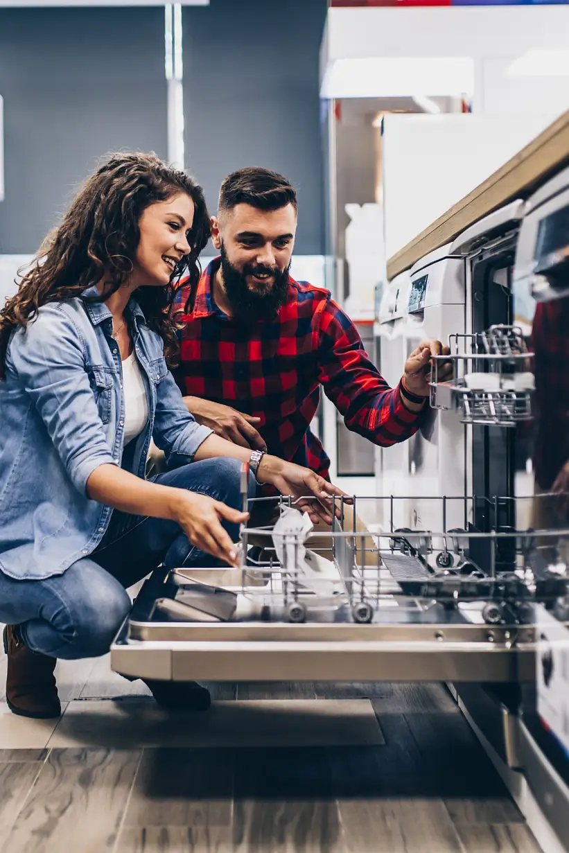 Beautiful and happy young couple buying dishwasher in modern appliances store.