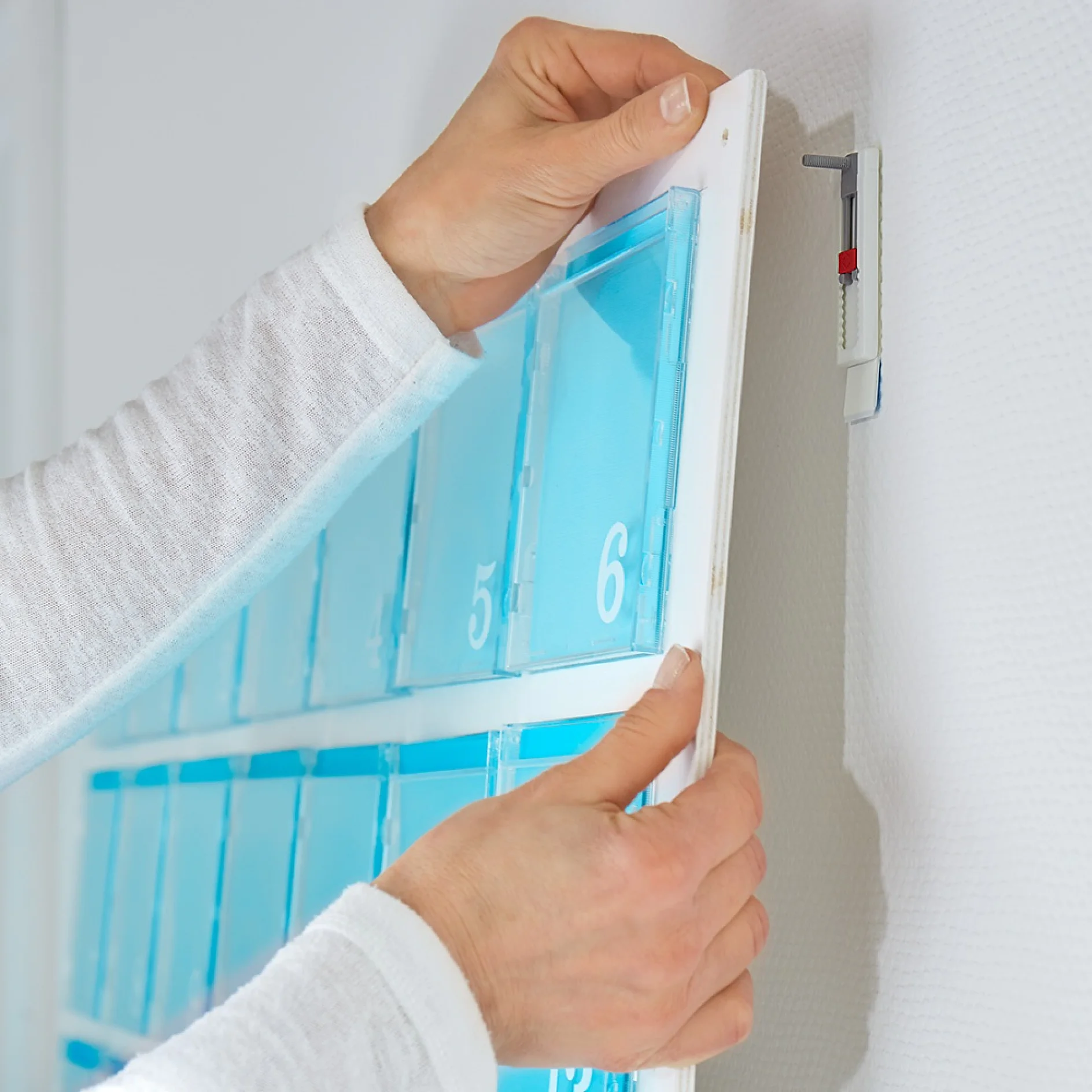 Hanging the DIY calendar using tesa® Adjustable Adhesive Nails for Wallpaper & Plaster 1kg