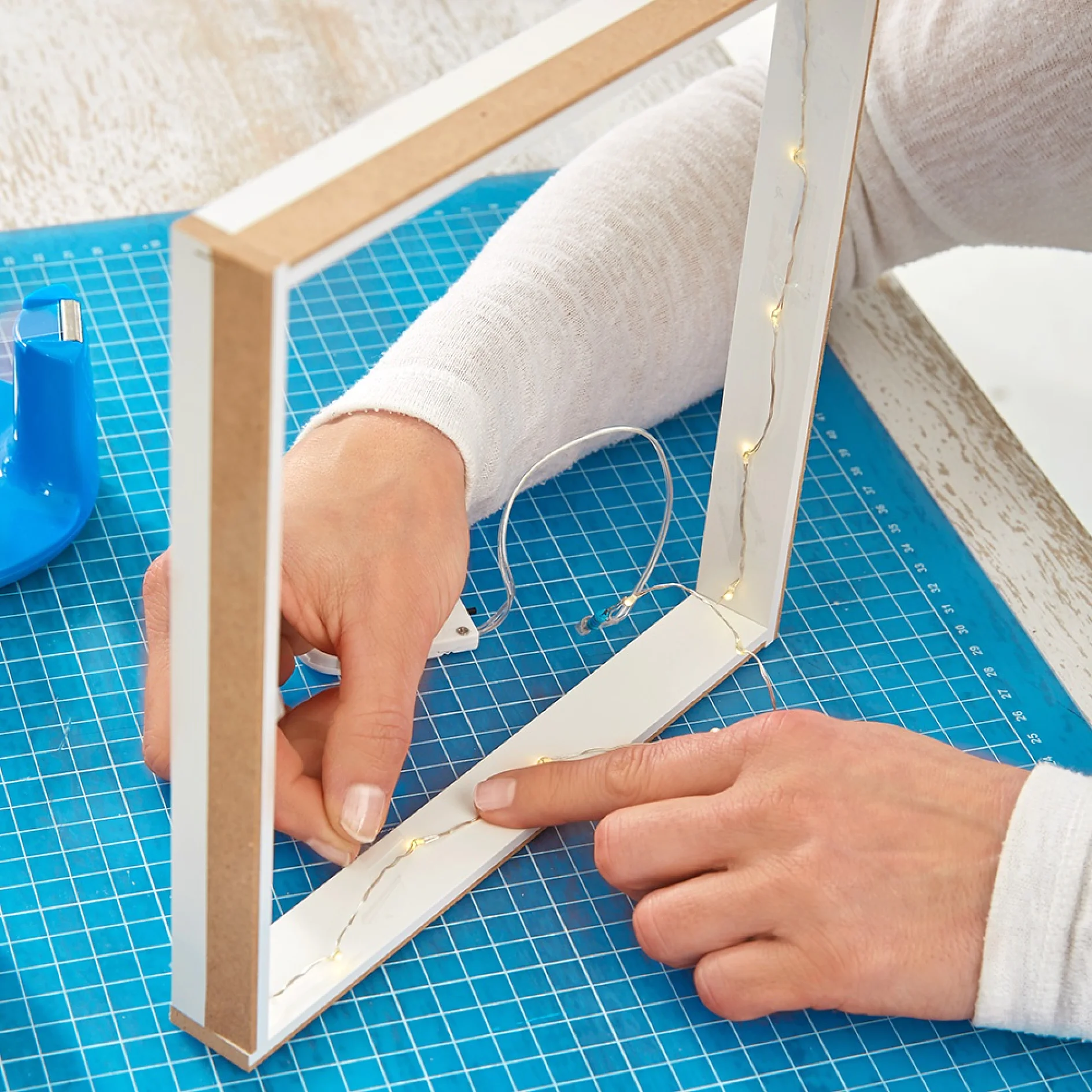 Affixing a string of lights using tesa Easy Cut® Desk Dispenser Compact while making a picture frame wall light.