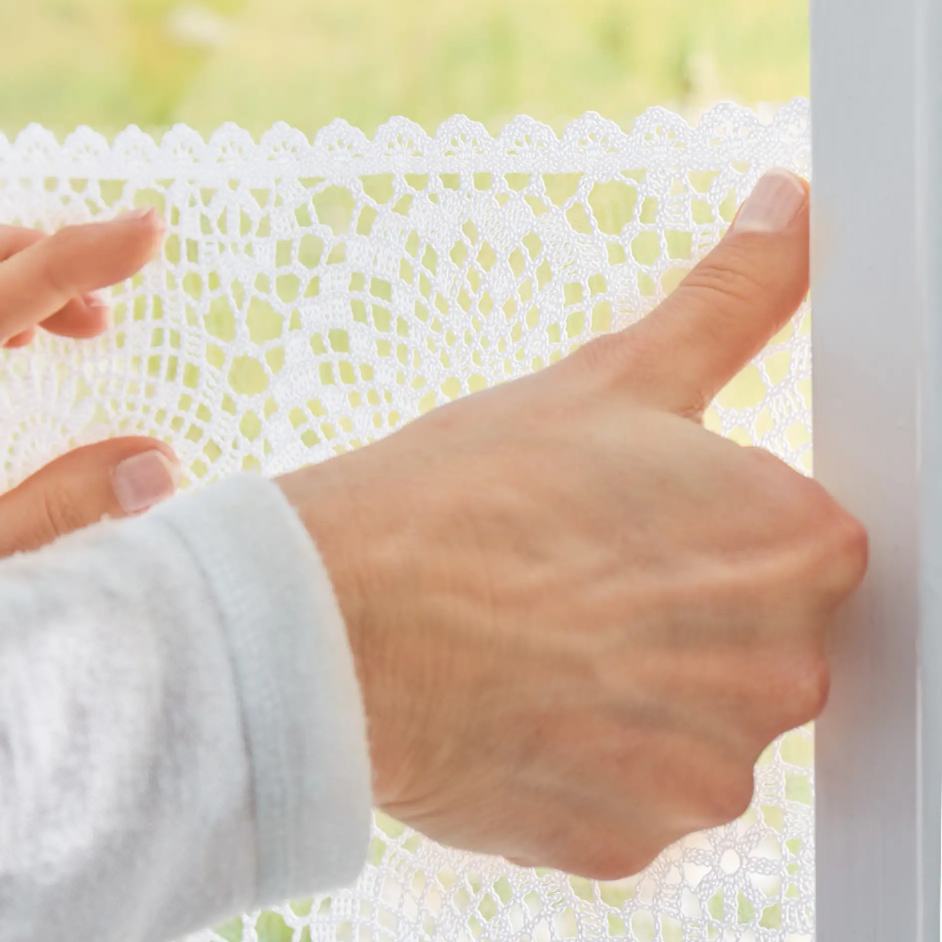 Applying the lace window treatment with tesa® Adhesive Strips for Transparent & Glass 0.2kg.