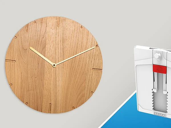 A wooden clock with a minimalistic design and golden hands is on the left. On the right is a white wall hook packaging with a modern design against a blue background, utilizing tesa tape for secure adhesion. (This text has been generated by AI)