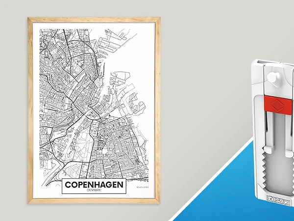 A framed map of Copenhagen, Denmark, is displayed on a white wall. Next to it on a blue surface is a white and red wall hanger featuring grooves and a hook for hanging items. (This text has been generated by AI)
