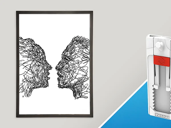 A framed abstract artwork depicting two faces in profile made from tangled lines is on the left. On the right, a small white and red wall fixture tool, secured with tesa tape, is positioned vertically against a blue and gray background. (This text has been generated by AI)