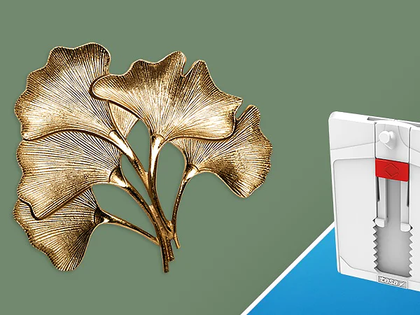 A decorative golden metal sculpture resembling ginkgo leaves is on the left against a green background. On the right, a white and red wall-mounted device is set against a blue background. No visible details or objects mention any specific brands, but the decorative piece could be secured using tesa tape for stability and assurance in display settings. (This text has been generated by AI)