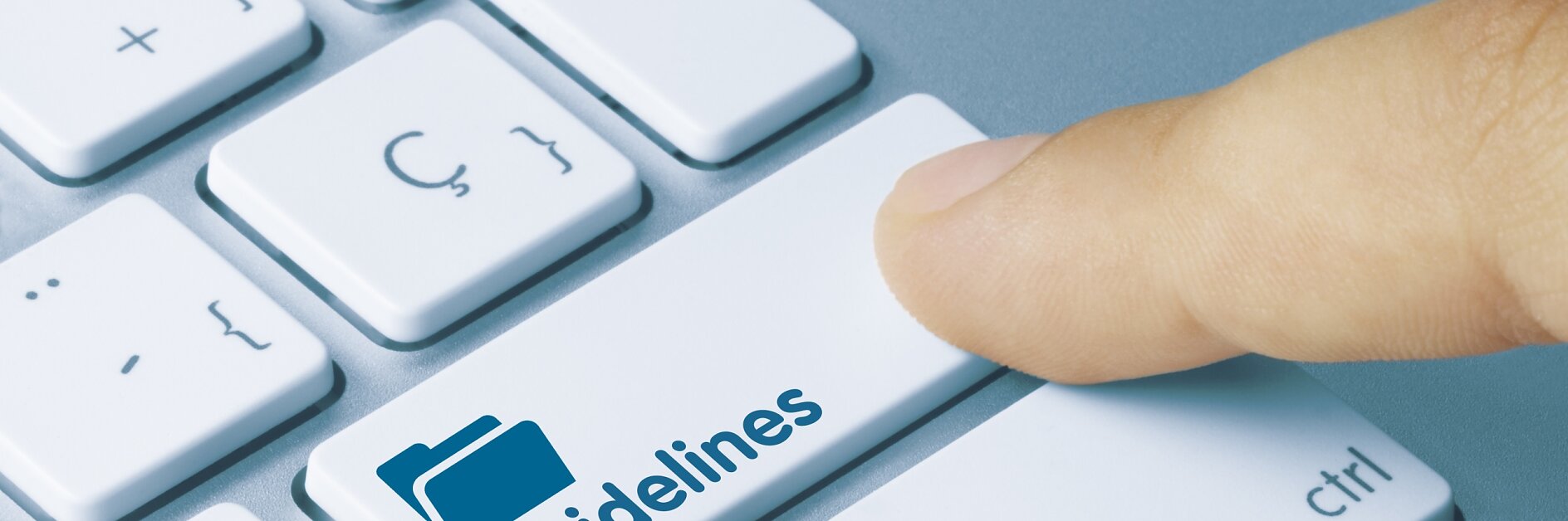Un doigt appuyant sur une touche blanche du clavier intitulée « Lignes directrices » avec une icône de dossier bleue. La touche est située entre les touches « Ruban tesa » et « Ctrl ». (This text has been generated by AI)