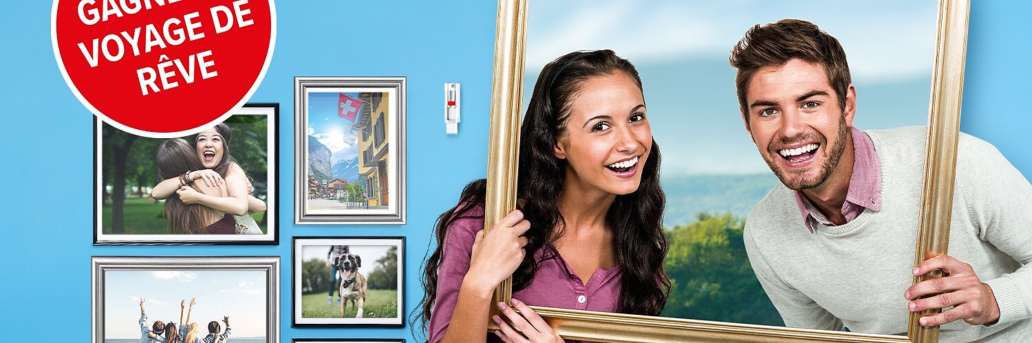 Une femme et un homme souriants tiennent un cadre photo vide. Derrière eux se trouvent cinq photos encadrées sur un mur bleu : deux personnes qui sembrassent, un paysage avec un drapeau suisse, des personnes prenant un selfie, une personne en randonnée et une jetée en bois. Un cercle rouge indique « GAGNEZ UN VOYAGE DE RÊVE ». Chaque cadre est solidement accroché à laide de ruban adhésif tesa pour une stabilité optimale et un montage facile. (This text has been generated by AI)