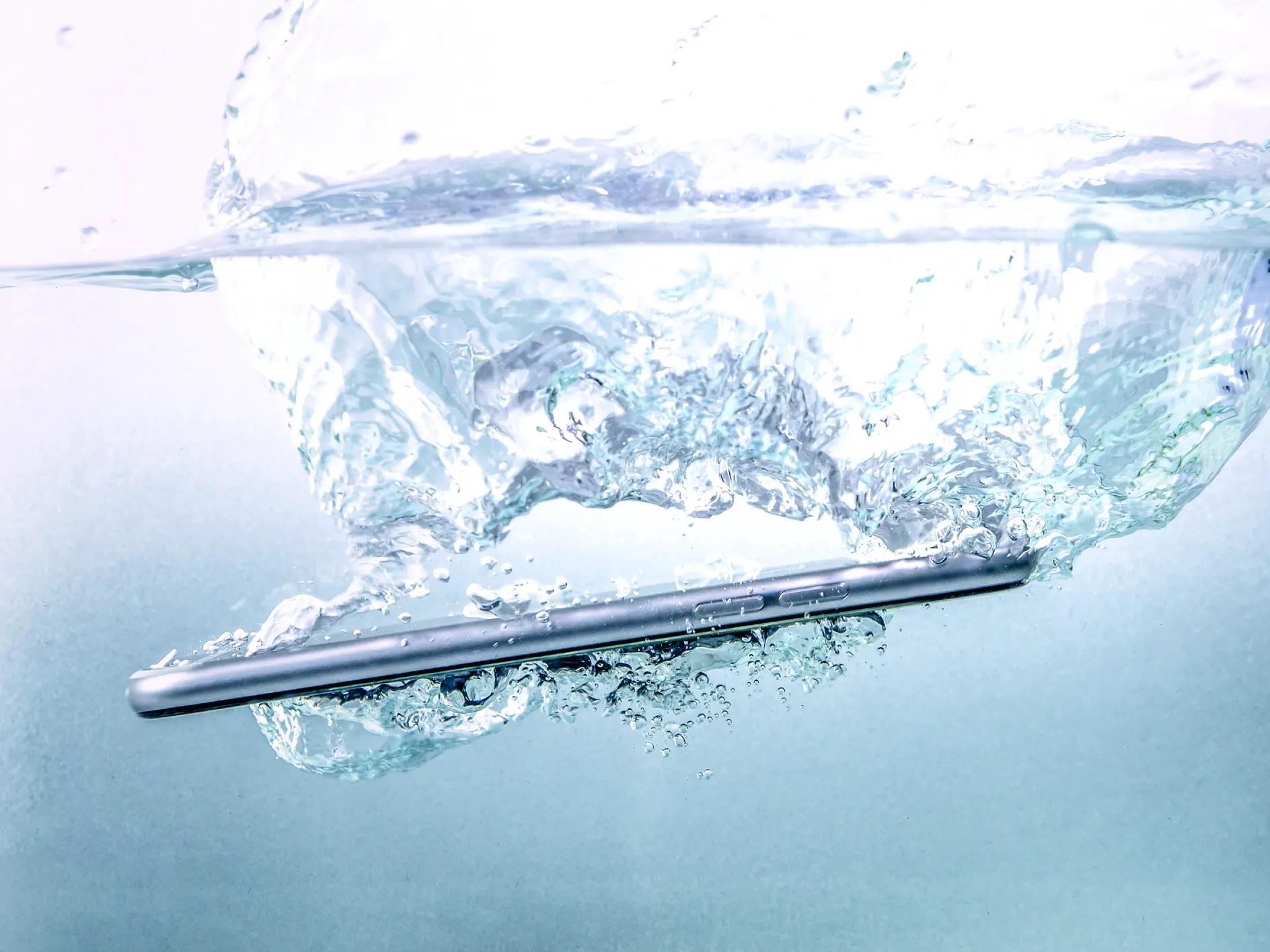 A smartphone submerged in water, creating bubbles and ripples in the surrounding liquid, is secured with tesa tape.