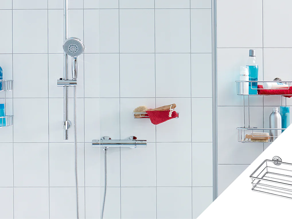 A white tiled shower with a chrome showerhead and controller. Three corner shelves hold toiletries including bottles and brushes. A red towel is draped over one shelf. An inset shows a wire rack attached with tesa tape suction cups. (This text has been generated by AI)