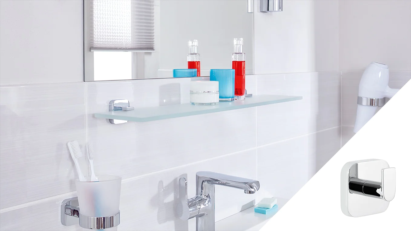 A modern bathroom features a silver faucet and a glass shelf with items on it, including red and blue bottles and a white candle. A toothbrush holder with two toothbrushes is on the counter. A chrome accessory is shown in a small inset on the right, held securely using tesa tape. (This text has been generated by AI)