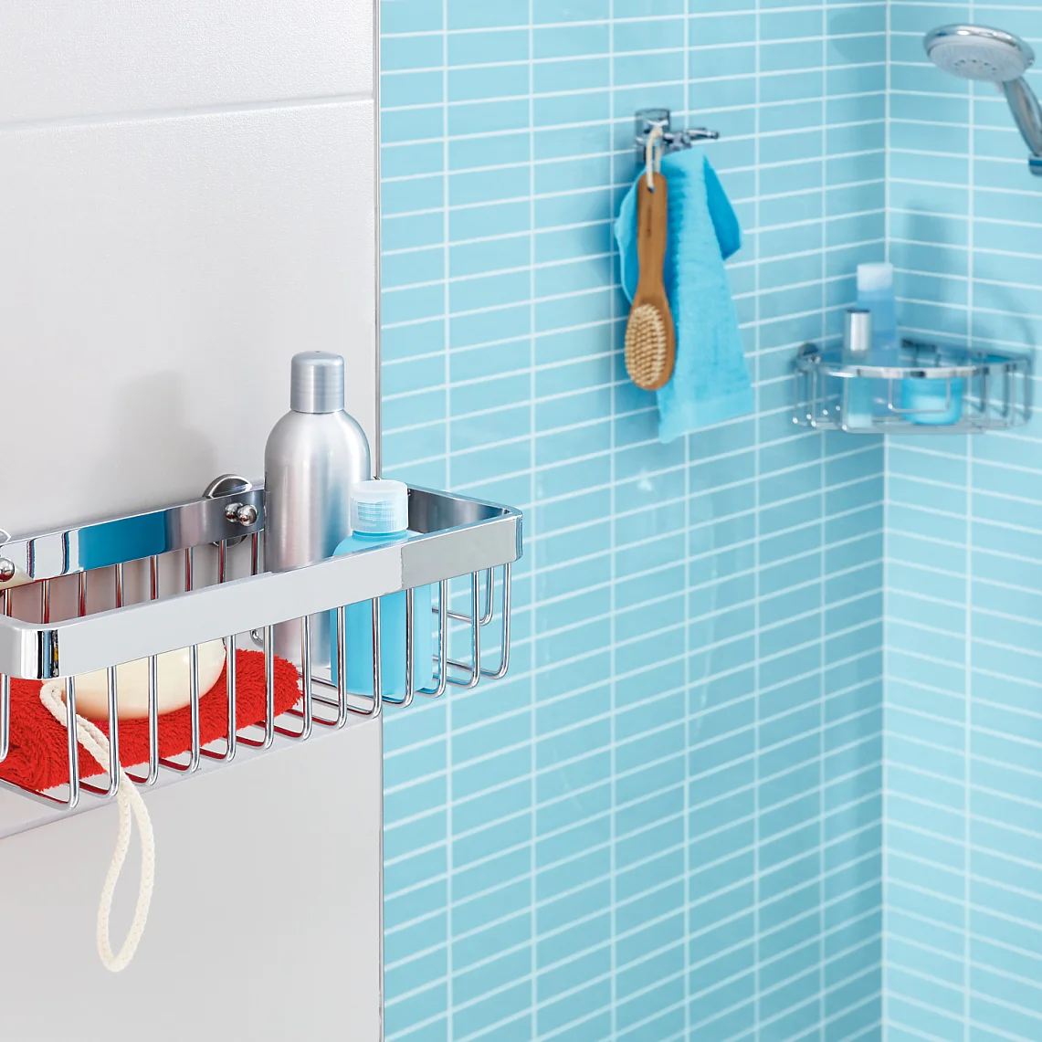 A modern bathroom with light blue tiles features a wall-mounted metal shower caddy holding a red cloth, a soap bar, and a bottle. A showerhead with an adjustable arm is on the right, along with a hanging washcloth and broom nearby. The installation is secured using tesa tape for added stability. (This text has been generated by AI)