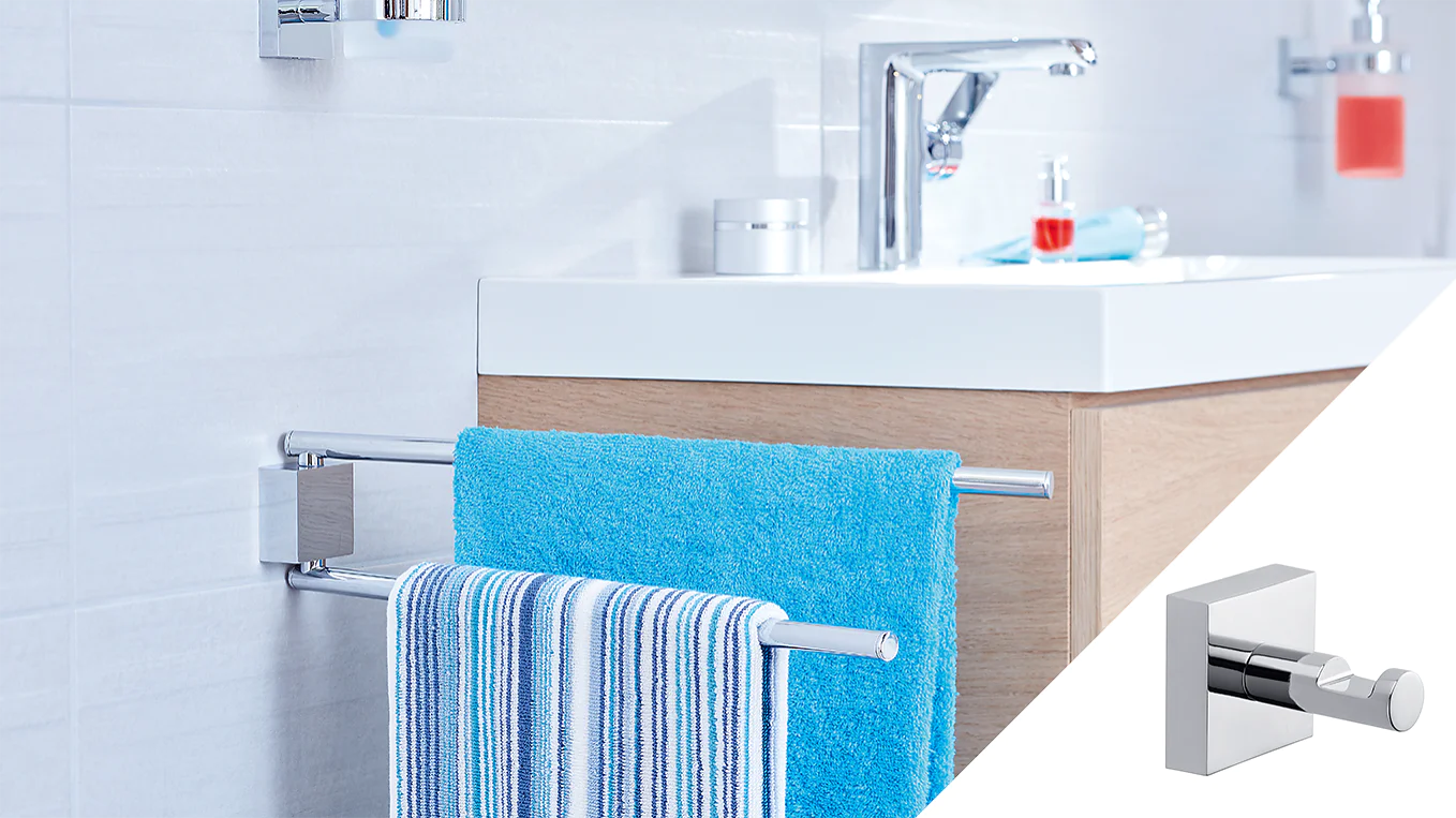 A bathroom features a white sink with a modern faucet on a wooden cabinet. Two towels, one blue and one striped, hang on a chrome towel rack attached to the side of the cabinet using tesa tape. A soap dispenser is visible on the sink. (This text has been generated by AI)