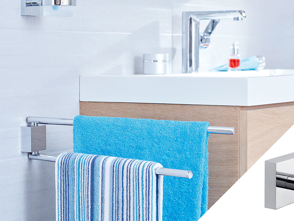 A bathroom features a white sink with a modern faucet on a wooden cabinet. Two towels, one blue and one striped, hang on a chrome towel rack attached to the side of the cabinet using tesa tape. A soap dispenser is visible on the sink. (This text has been generated by AI)