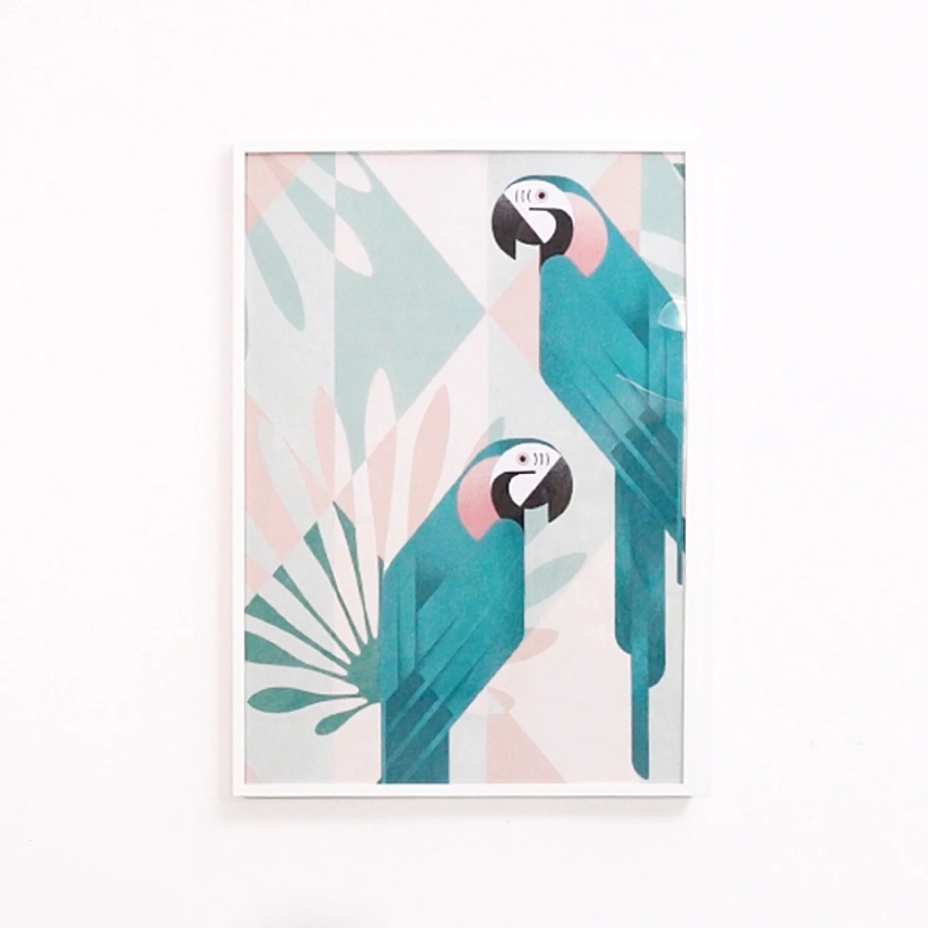 Framed artwork features two stylized blue and pink parrots with geometric shapes in the background. The design is minimalistic with a pastel color palette, mounted on a plain white wall using tesa tape. (This text has been generated by AI)