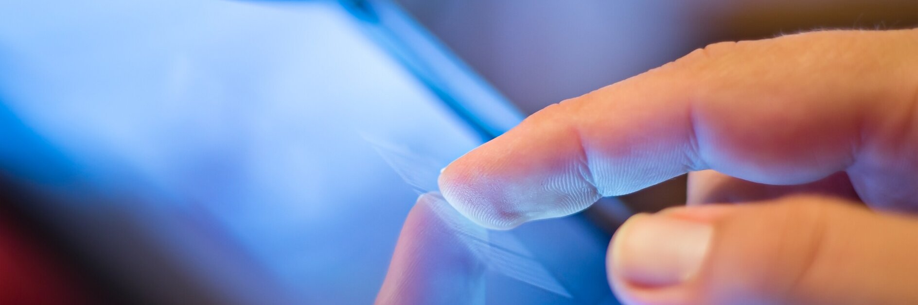 Hand touching a tablet screen indoors, reflecting finger on the glass surface, highlighting touchscreen interaction technology.