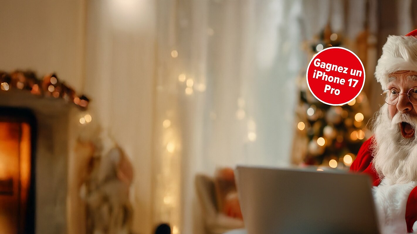Une personne habillée en Père Noël est assise près d'une cheminée et d'un sapin de Noël, surprise devant un ordinateur portable. Un autocollant rouge indique "Gagnez un iPhone 17 Pro". (This text has been generated by AI)