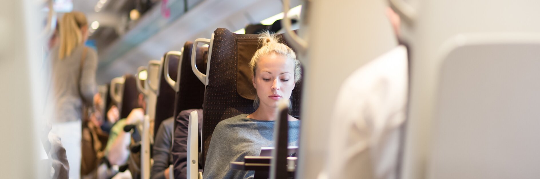 Femme blonde caucasienne voyageant décontractée en train. Train plein de passagers allant au travail dans les transports publics à l'heure de pointe. Image d'archives Adobe