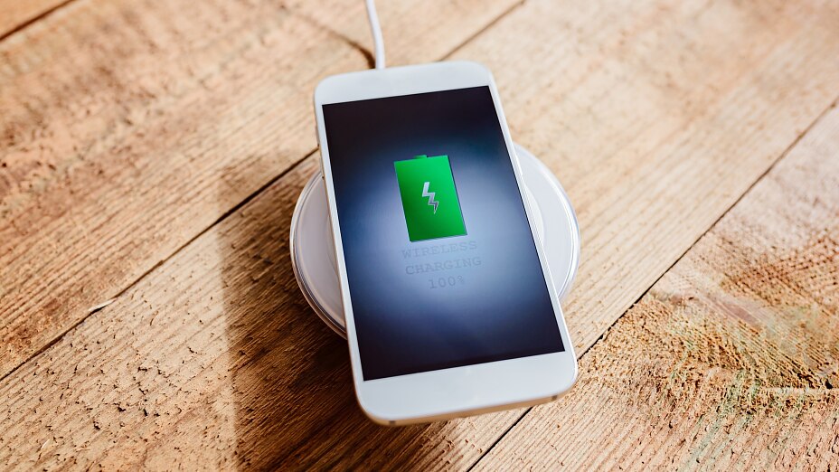 Fehér színű okostelefon a töltőállványon.