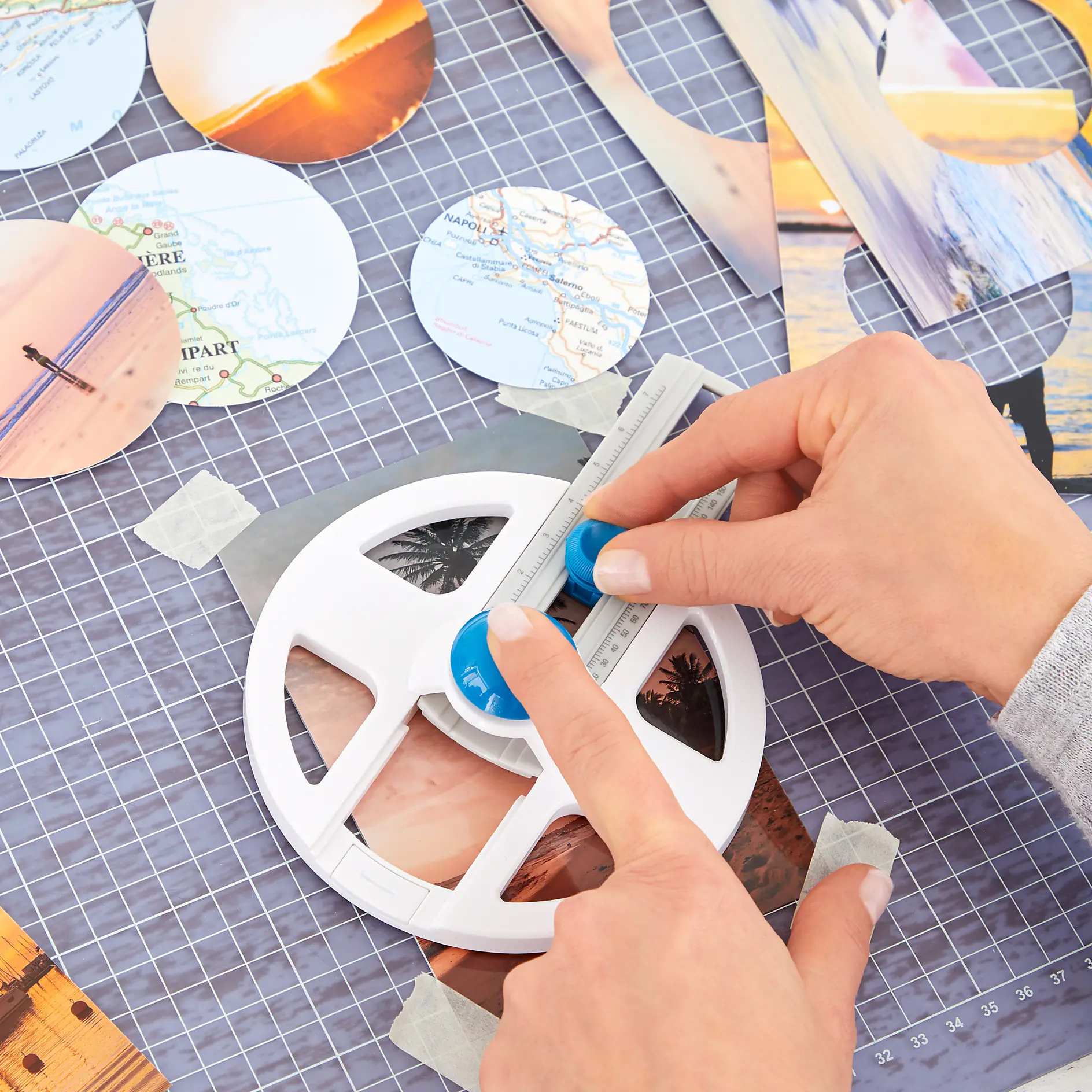 A person uses a circular cutter to trim a piece of paper with a photograph printed on it. The workspace has a grid mat and multiple circular cutouts, including maps and sunset images. tesa tape is used to secure the paper. (This text has been generated by AI)