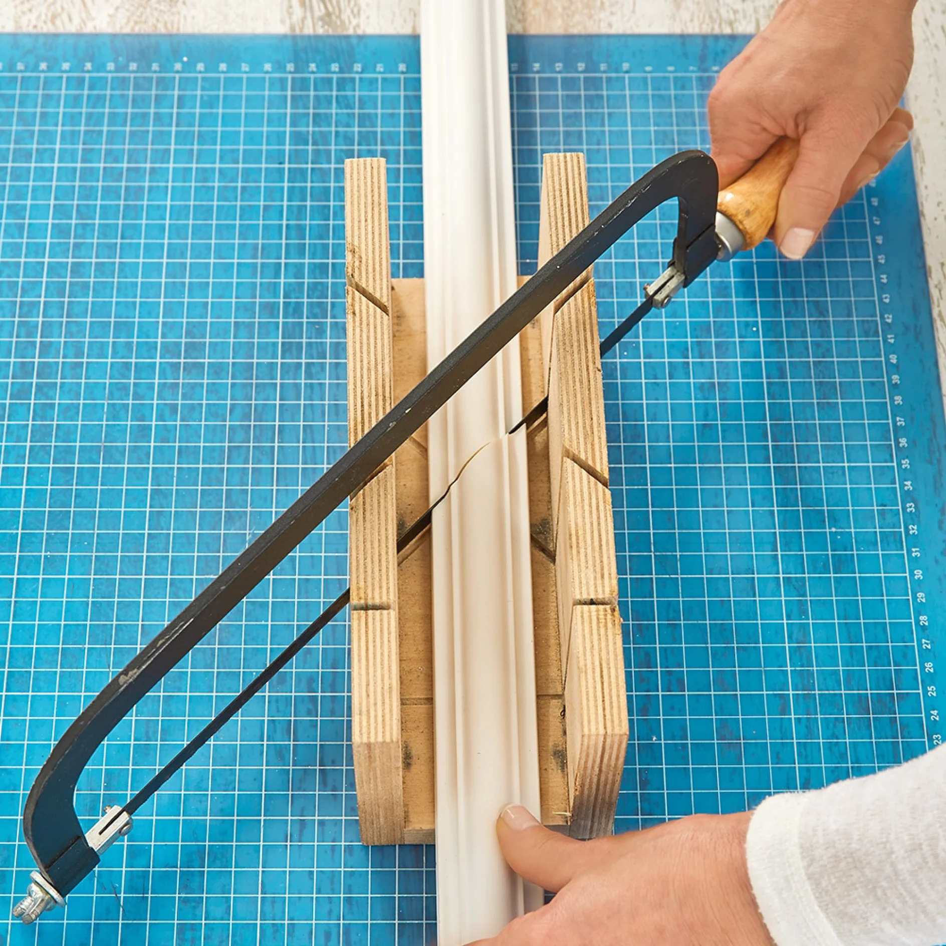 Sawing lengths of decorative plasterwork while making a DIY headboard.