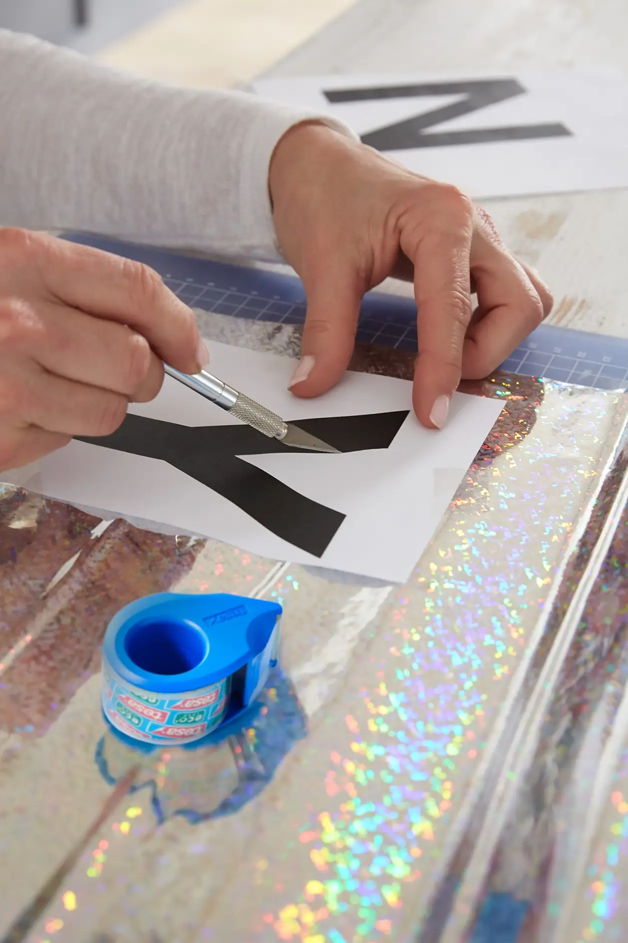 Fix the holography film on the cutting mat with tesafilm® and arrange the single letters on It; cut out the letters using a cutter.