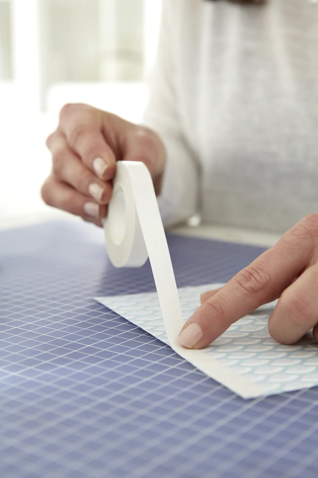 Apply a strip of tesa® double-sided adhesive tape on the patterned side of one of the folded surfaces.