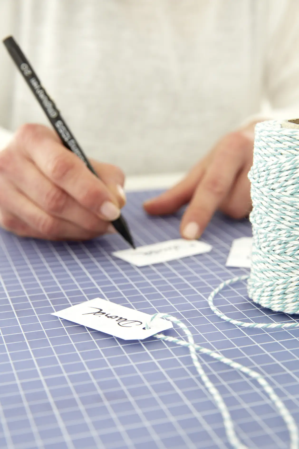 Cut small labels from the remaining paper, write names on them using the calligraphy pen, punch a hole on the upper side and attach the labels to the pouch using the string.
