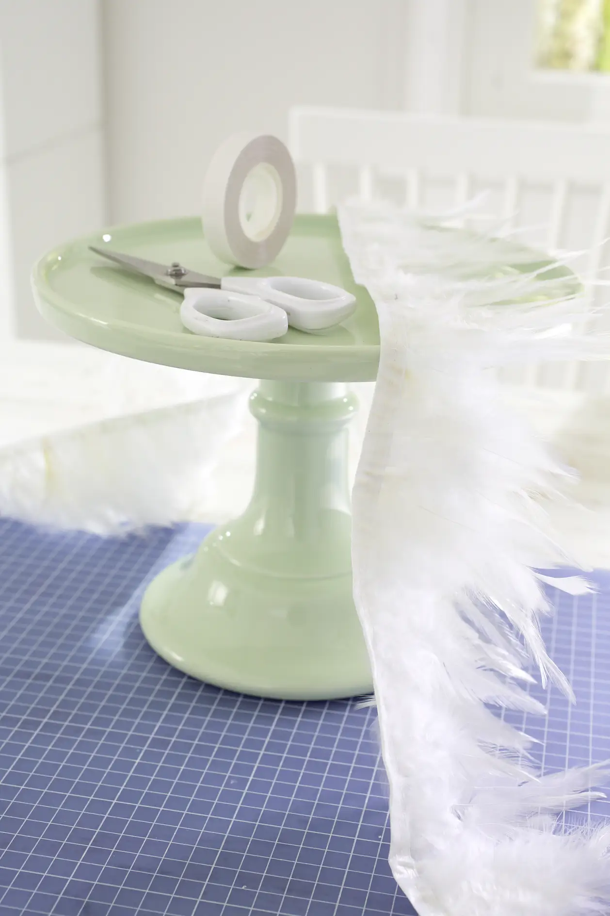 Cake stand, white feather border (length: circumference of the cake stand), scissors, tesa® double-sided adhesive tape