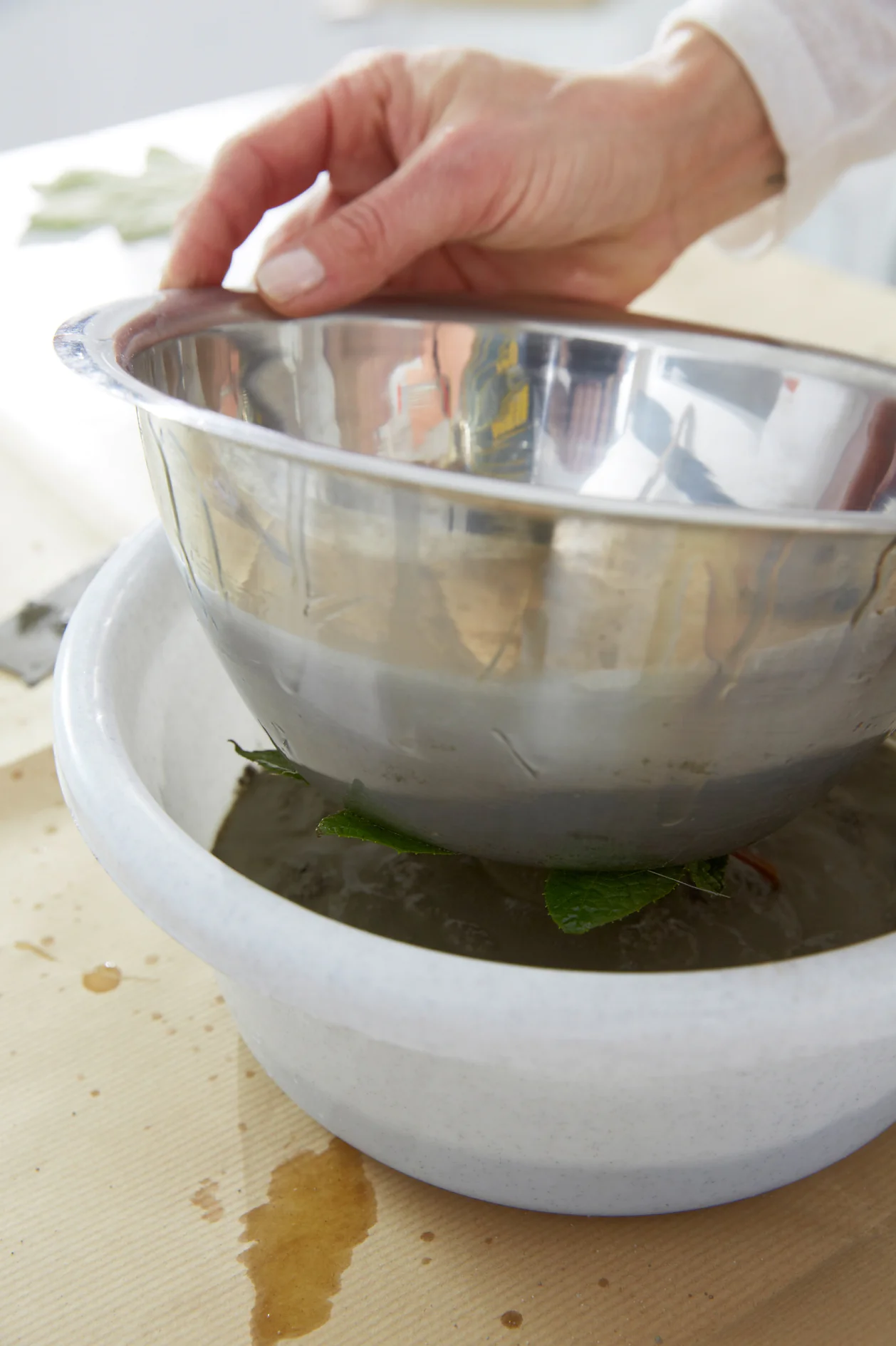 Pour the mixture into the larger bowl, place the smaller bowl with the leaf inside. Press the smaller bowl down.