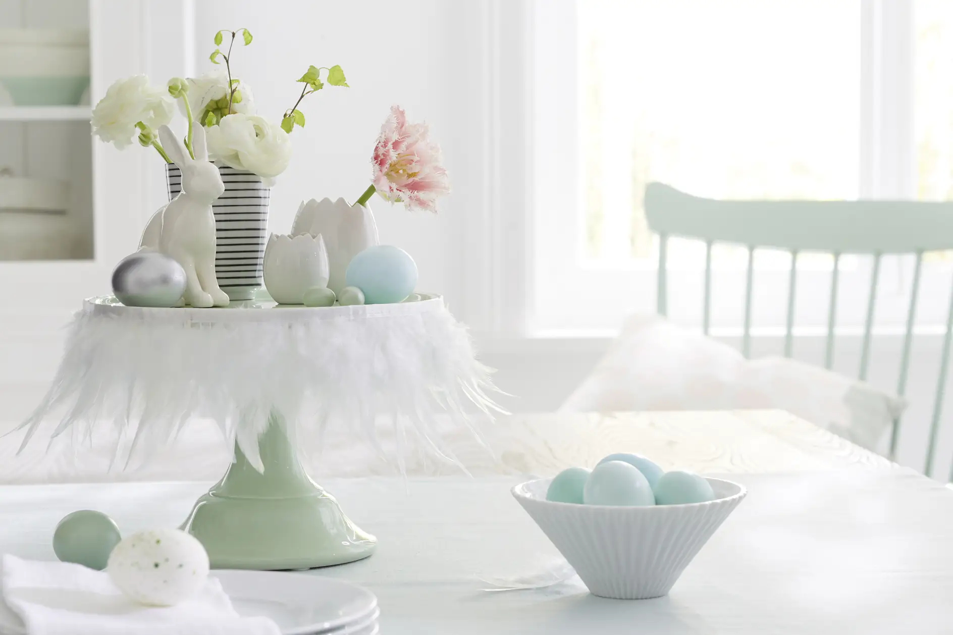White feathers transform a cake stand into a Easter stage for bunnies, flowers and eggs. The secret weapon for this quick decoration idea: tesa® double-sided adhesive tape.