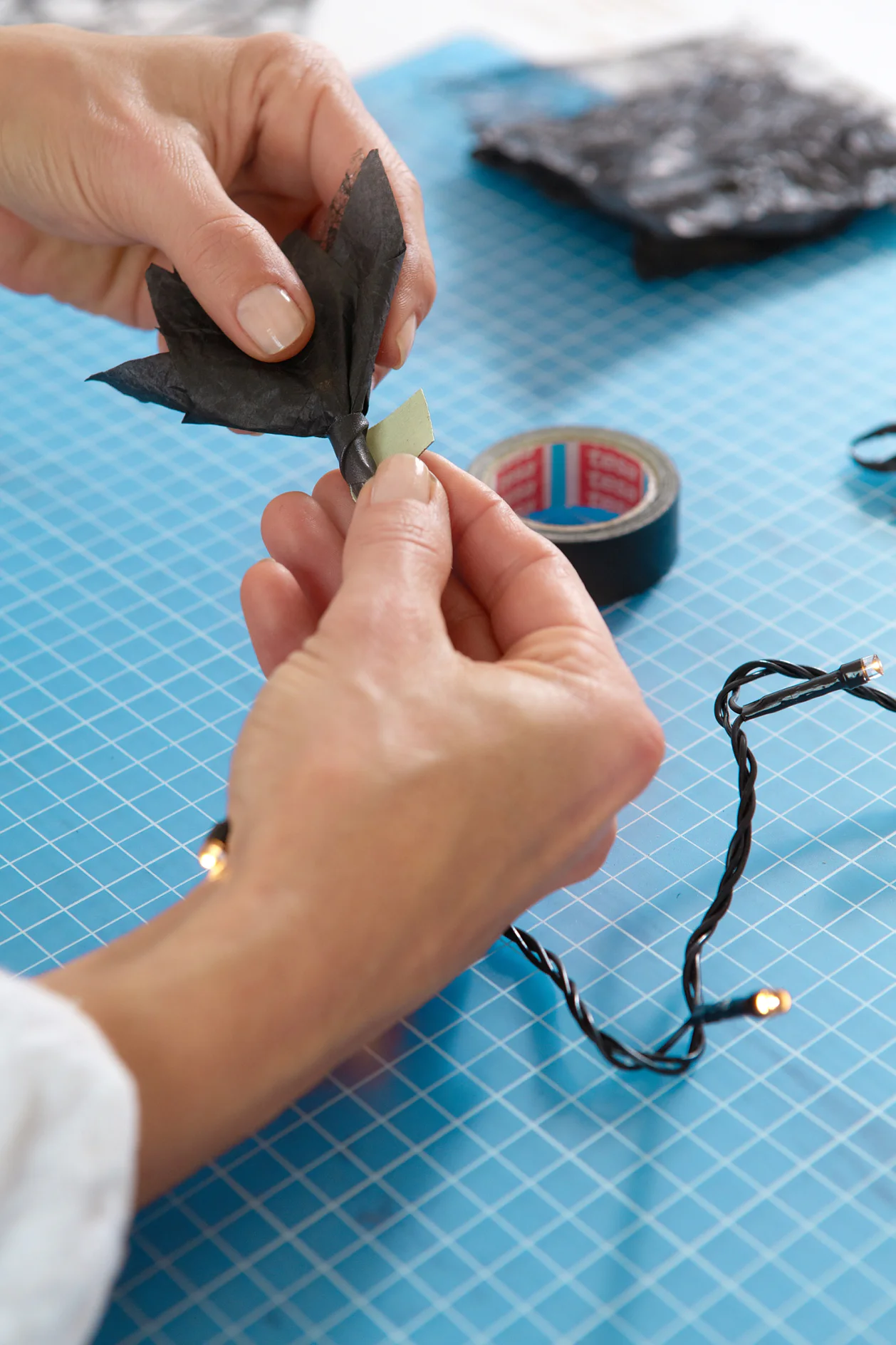 Die Blütenblätter nach oben halten und die Blüte mit tesa extra Power® Perfect Gewebeband an der Kette fixieren.