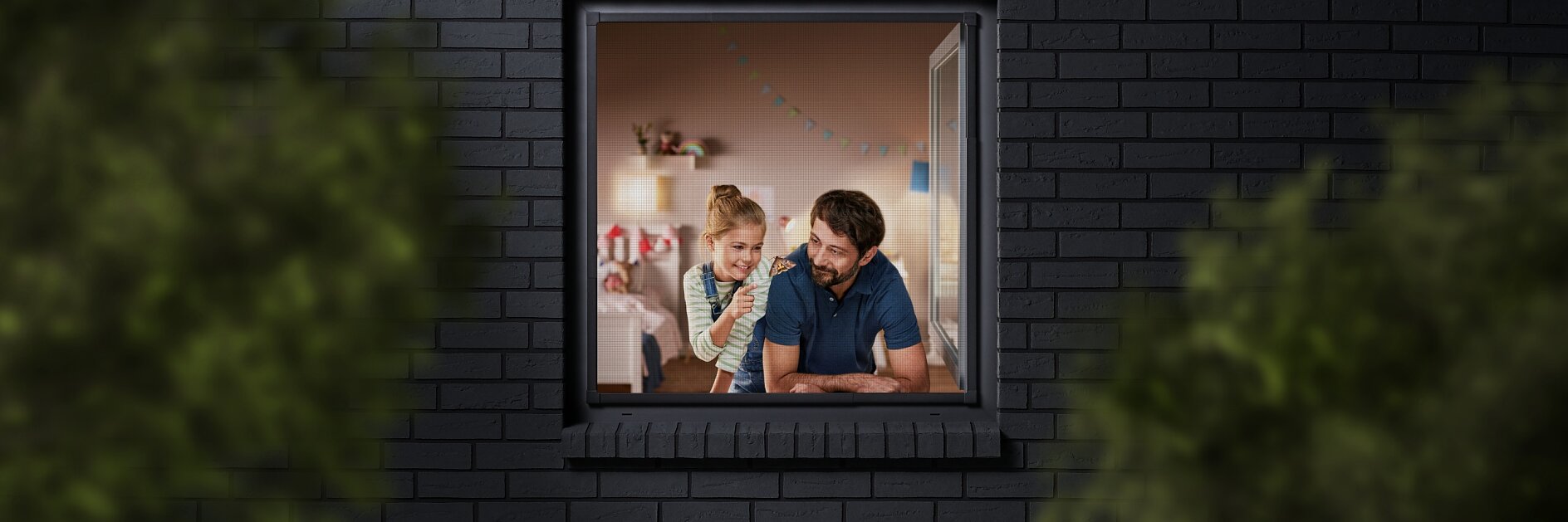 A man and a child are seen through a window, looking into a room decorated with colorful bunting. The building has dark brick walls, and the view is partially framed by blurred greenery. The man is wearing a blue shirt, and the child is sitting beside him. (This text has been generated by AI)