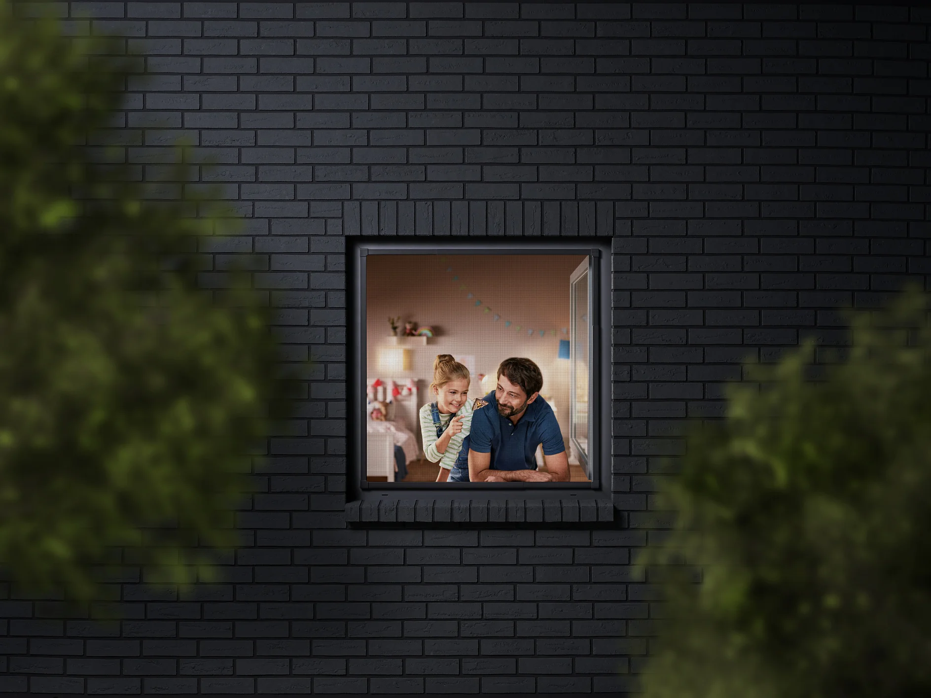 A man and a child are seen through a window, looking into a room decorated with colorful bunting. The building has dark brick walls, and the view is partially framed by blurred greenery. The man is wearing a blue shirt, and the child is sitting beside him. (This text has been generated by AI)