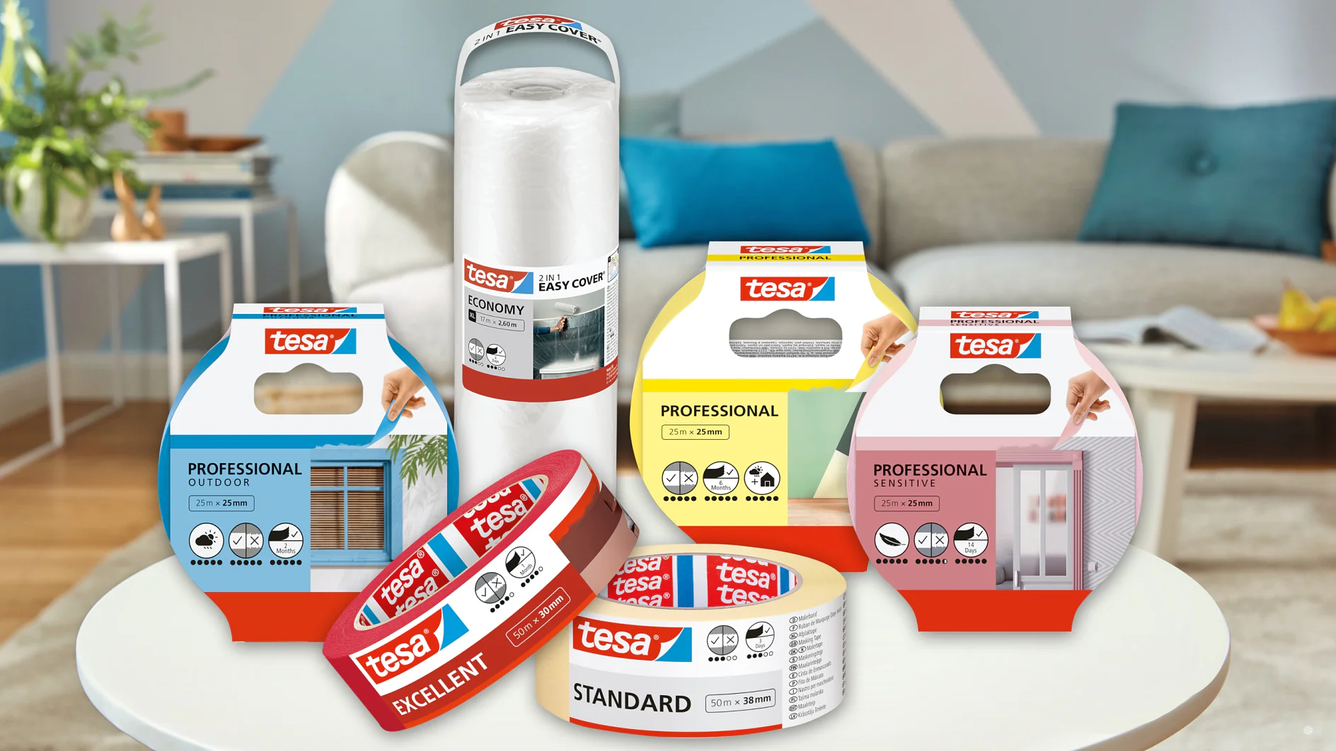 Una varietà di prodotti adesivi tesa sono esposti su un tavolo in un ambiente soggiorno. I prodotti includono nastri tesa Professional, Excellent e Standard, insieme a Easy Cover e Adhesion Solution. Un divano e un tavolo sono sullo sfondo. (This text has been generated by AI)