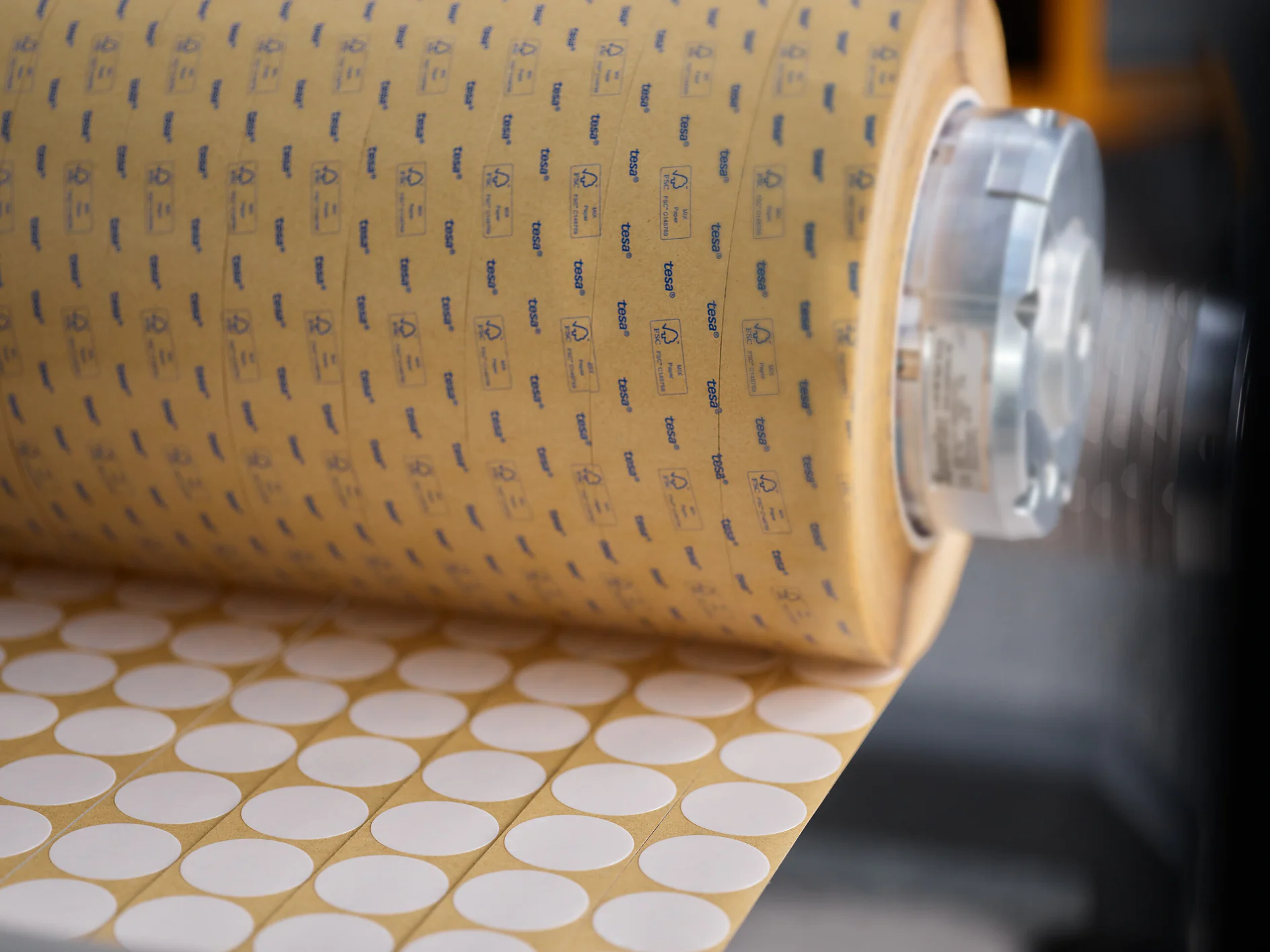 tesa branded roll of circular adhesive labels being dispensed in an industrial setting (This text has been generated by AI)