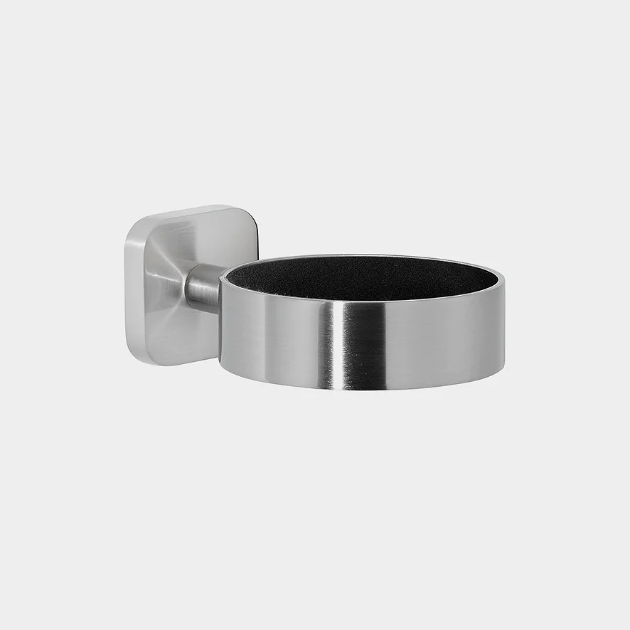 Portaoggetti da parete in acciaio inossidabile con design cilindrico e base quadrata. L'interno sembra essere rivestito con un materiale scuro. Il supporto a parete è fissato al lato sinistro del portaoggetti con nastro tesa. (This text has been generated by AI)