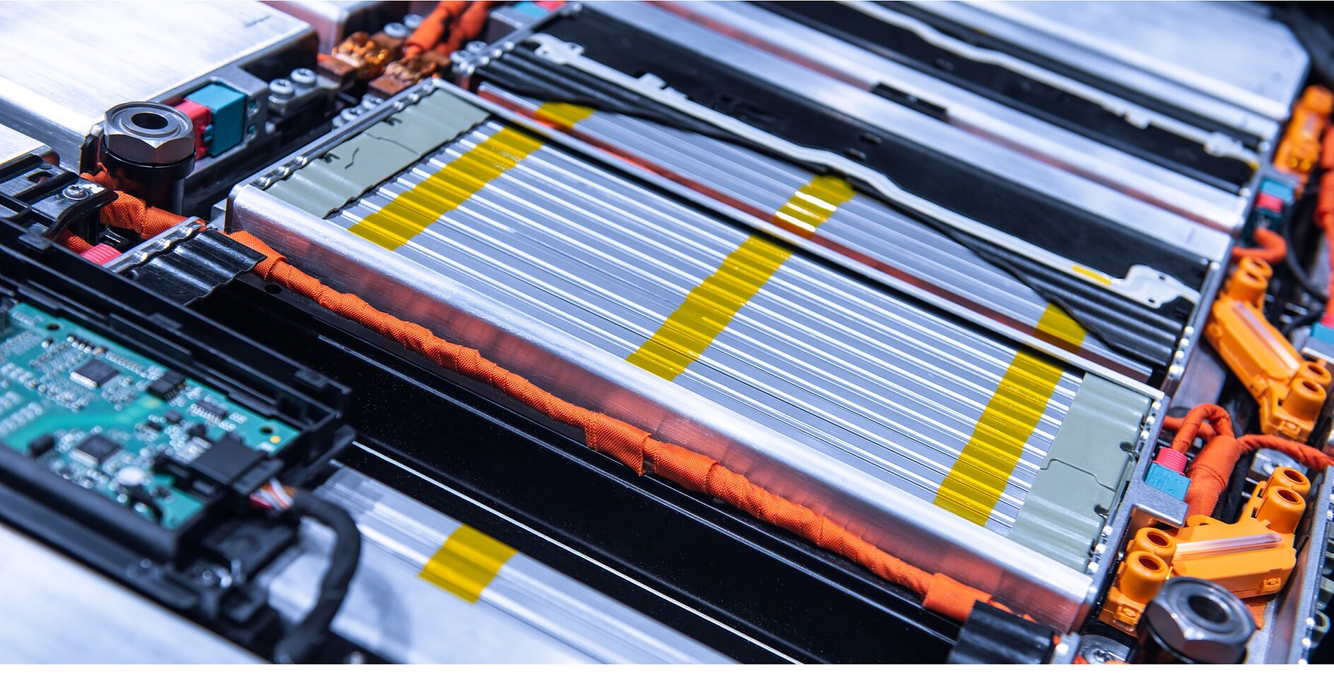 Close-up of a lithium-ion battery pack with exposed metal cells and bright orange electrical connectors. Visible circuit board and yellow safety markings highlight the components within the battery casing, including the use of tesa tape for secure insulation. (This text has been generated by AI)