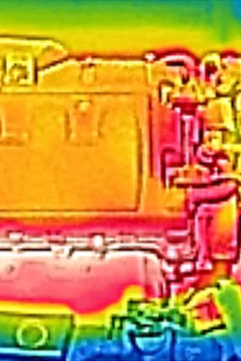 Thermal image of a car engine. The engine appears in warm colors, predominantly red and orange, indicating heat. Cooler colors, such as blue and green, surround the engine, suggesting lower temperatures in those areas. (This text has been generated by AI)