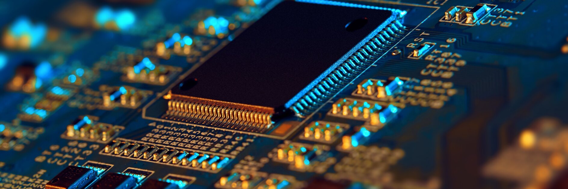 Close-up of a computer motherboard with a central processor unit. The image highlights circuit paths and electronic components in blue and orange lighting, providing a detailed view of the intricate motherboard design.