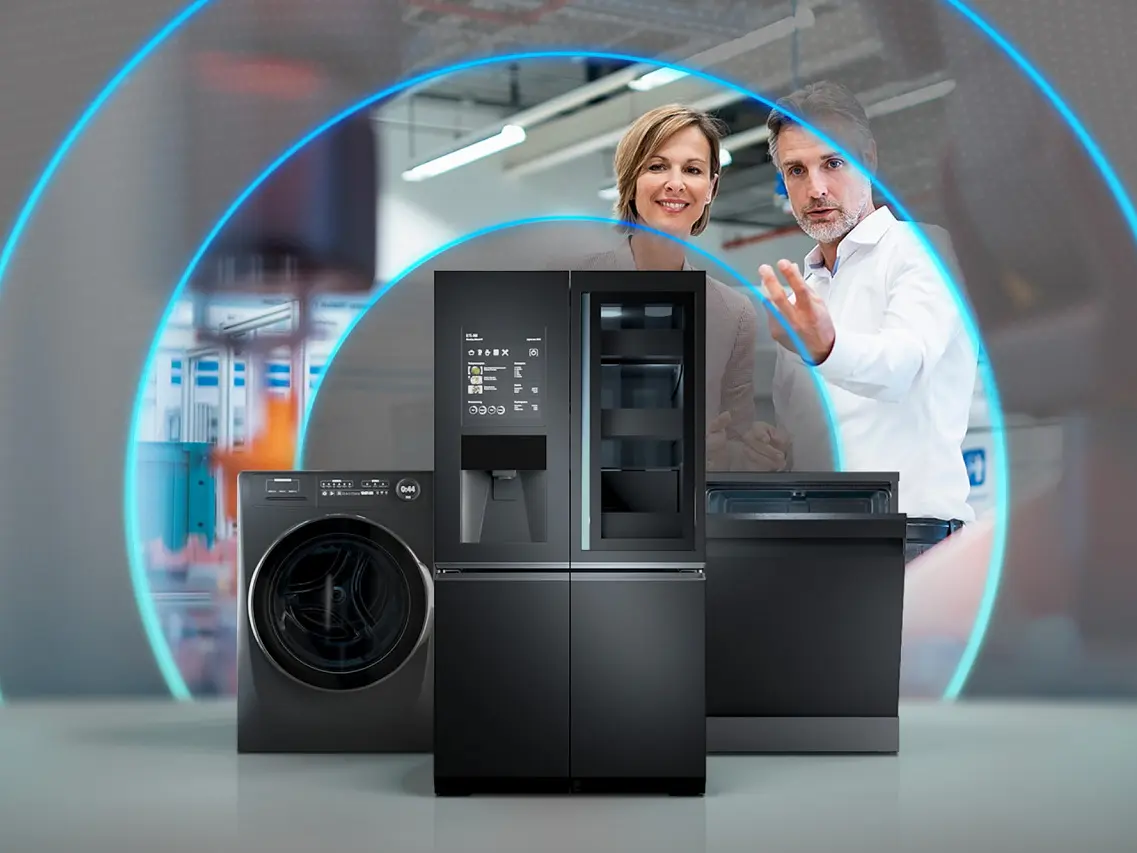Two people gesturing towards sleek black kitchen appliances, such as a washing machine, refrigerator, and dishwasher. The image showcases a modern setting with blue light arcs surrounding the appliances.