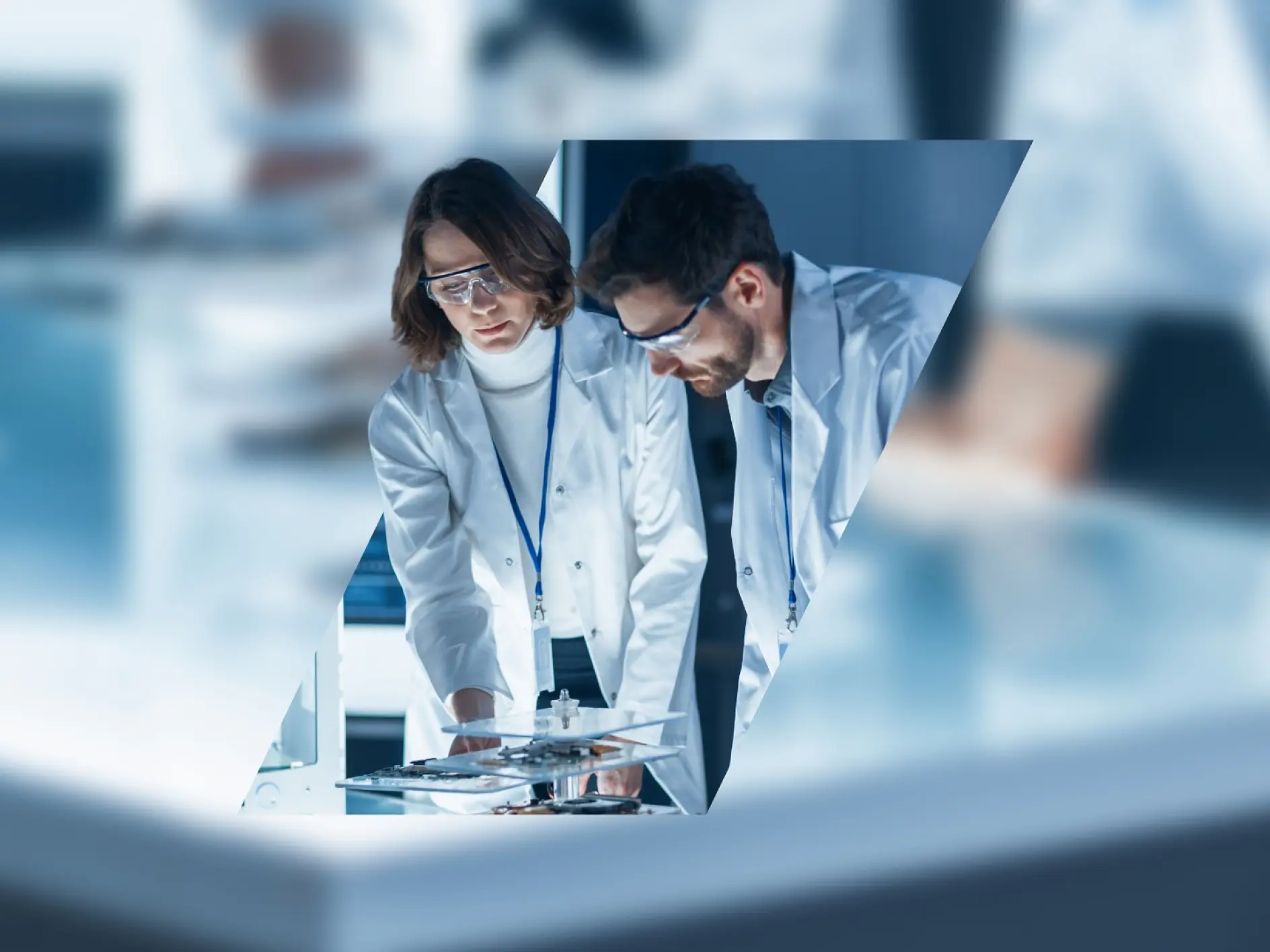Two scientists in a laboratory are wearing white lab coats and safety goggles. They are examining a piece of equipment on a table secured with tesa tape. The image is framed in a geometric shape against a blurred laboratory background. (This text has been generated by AI)