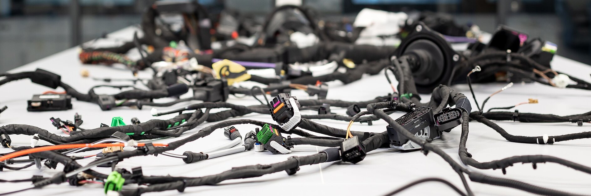 tesa wiring harnesses spread out on a white table in a bright industrial workspace with large windows in the background