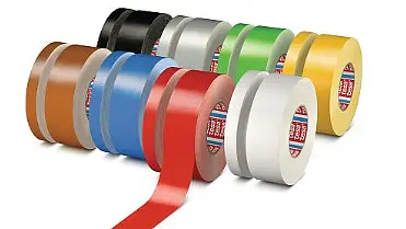 A collection of ten rolls of tesa tape is arranged in a triangular formation. The rolls are in various colors including brown, blue, red, black, gray, green, silver, white, yellow, and another shade of gray.