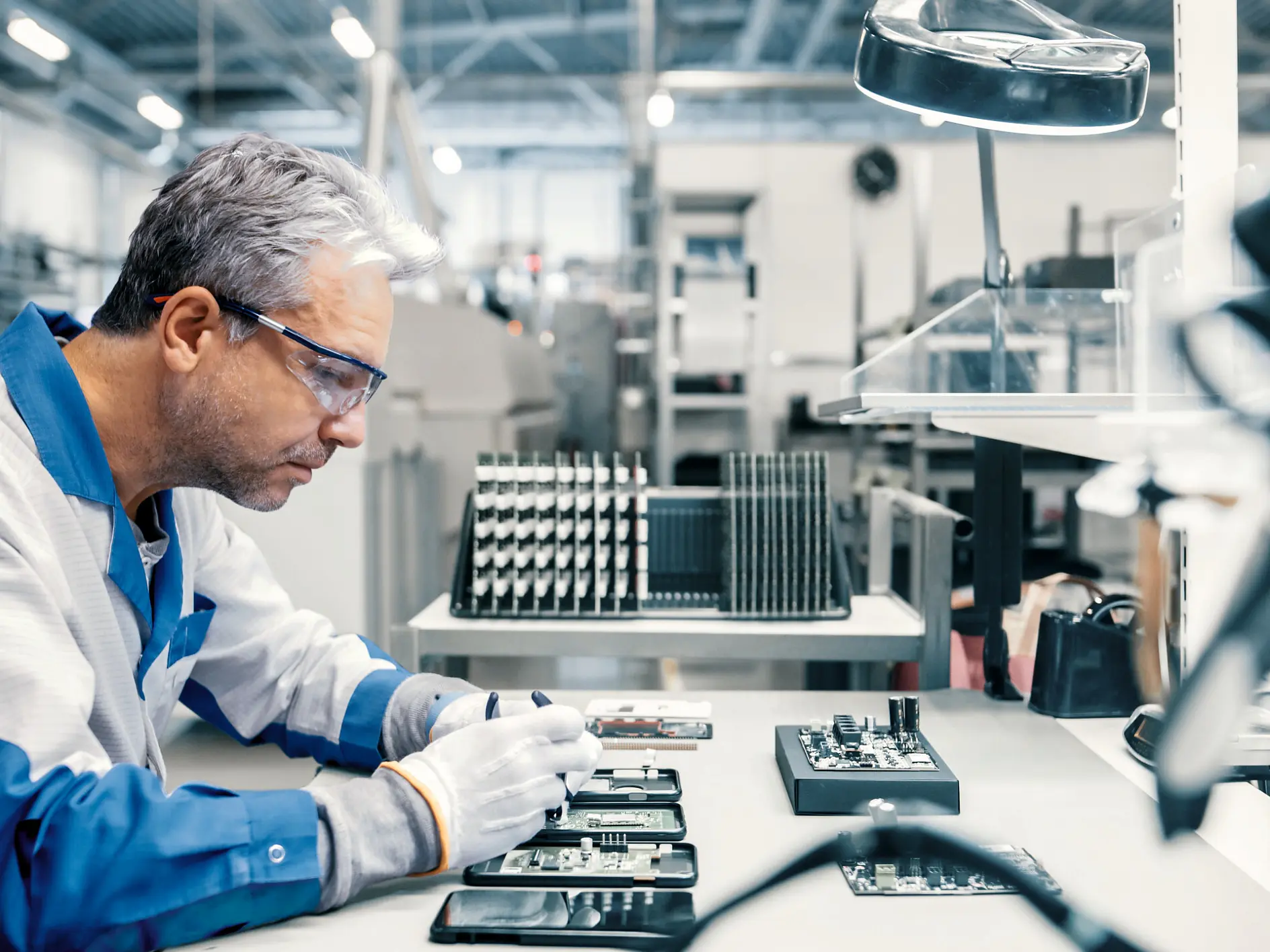 tesa technician assembling electronic components at a workstation inside a clean, well-lit manufacturing facility