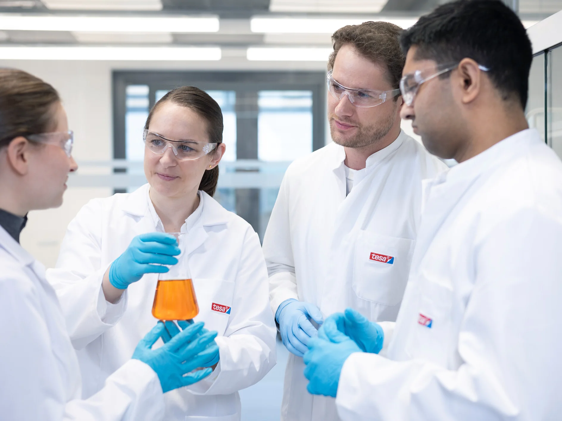 Komanda dirba kartu mokslinėje laboratorijoje, pabrėžiant bendradarbiavimą ir techninį tobulėjimą.