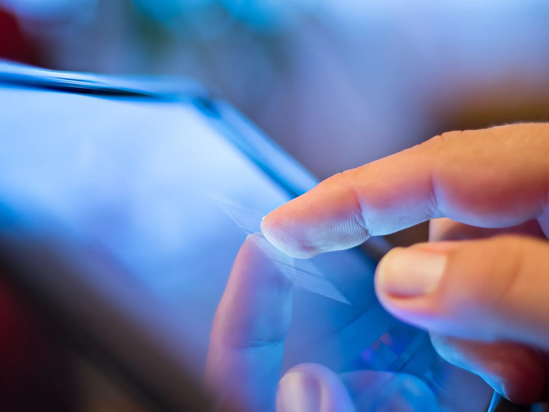 Hand touching a tablet screen indoors, reflecting finger on the glass surface, highlighting touchscreen interaction technology. (This text has been generated by AI)